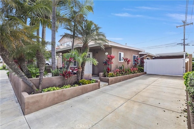 view of front of property with a gate, driveway, and stucco siding