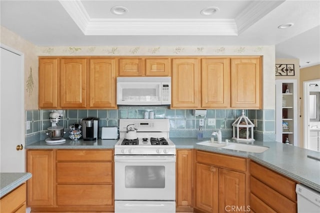 kitchen featuring a tray ceiling, white appliances, a sink, and crown molding