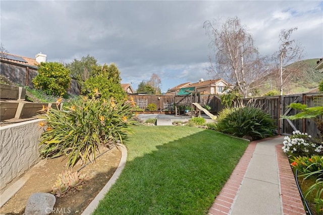 view of yard with a fenced backyard and a playground