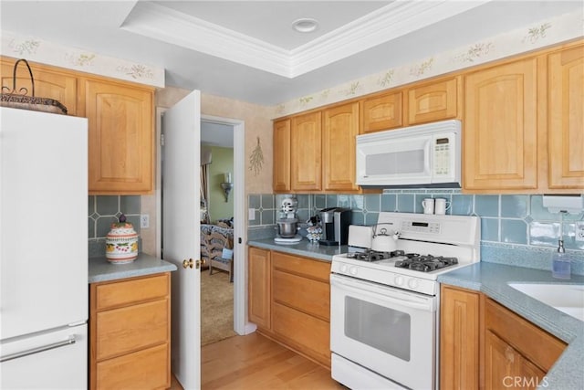 kitchen featuring light wood-style flooring, white appliances, ornamental molding, backsplash, and a tray ceiling