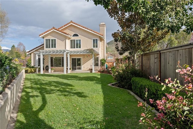 rear view of property featuring a yard, a chimney, stucco siding, a pergola, and a fenced backyard