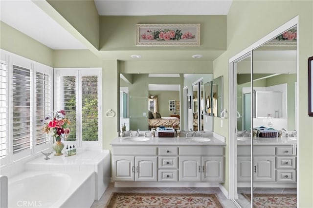 full bath featuring double vanity, a sink, a bath, and tile patterned floors