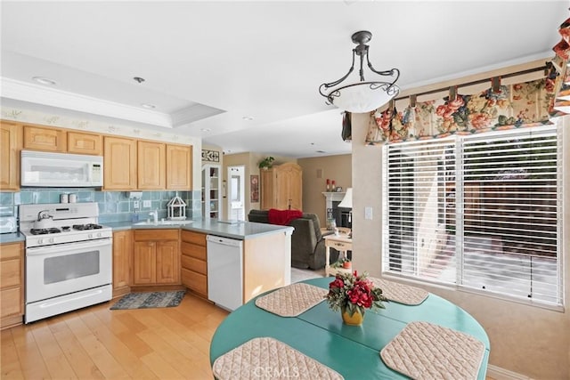 kitchen with a tray ceiling, backsplash, light brown cabinets, white appliances, and a peninsula