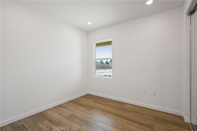 unfurnished room with baseboards, wood finished floors, and recessed lighting