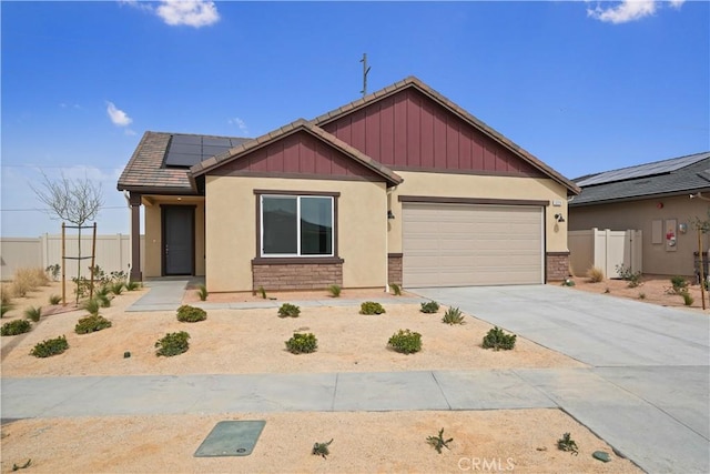 view of front of home with solar panels, concrete driveway, a tile roof, an attached garage, and fence