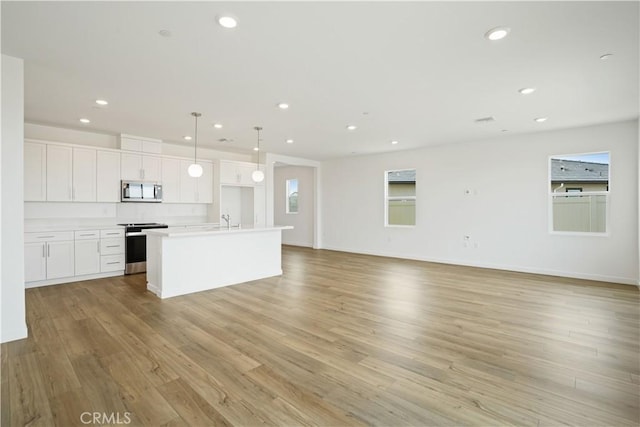 kitchen featuring white cabinetry, appliances with stainless steel finishes, open floor plan, and a sink