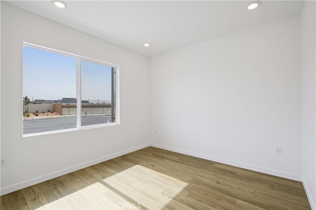 unfurnished room with recessed lighting, baseboards, and wood finished floors