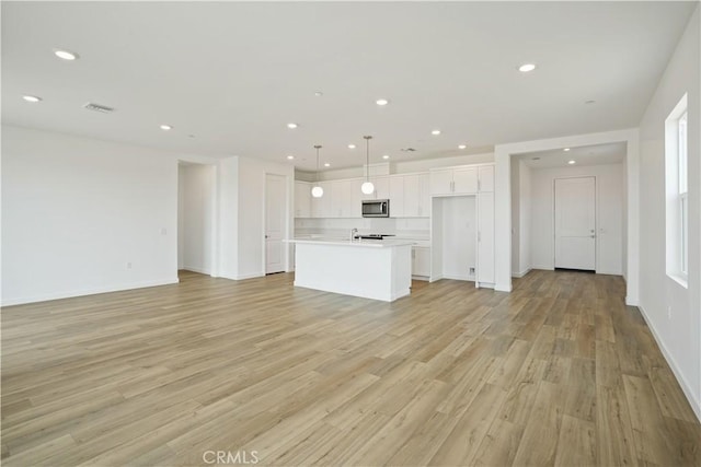 unfurnished living room with baseboards, light wood-style flooring, visible vents, and recessed lighting