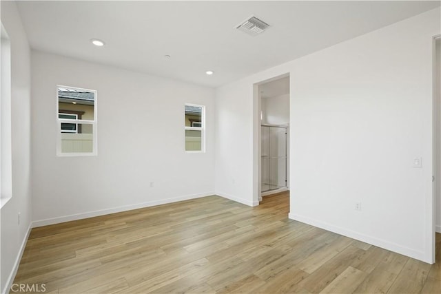 empty room with light wood finished floors, baseboards, visible vents, a wealth of natural light, and recessed lighting