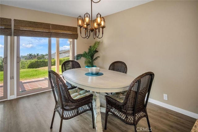 dining room with a chandelier, baseboards, and wood finished floors