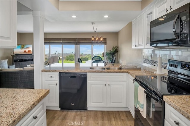 kitchen featuring light wood finished floors, white cabinets, decorative backsplash, black appliances, and a sink