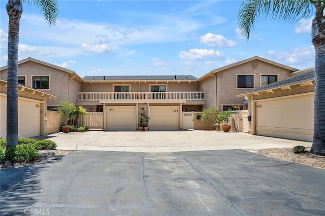 view of front of home featuring driveway, a garage, fence, and stucco siding