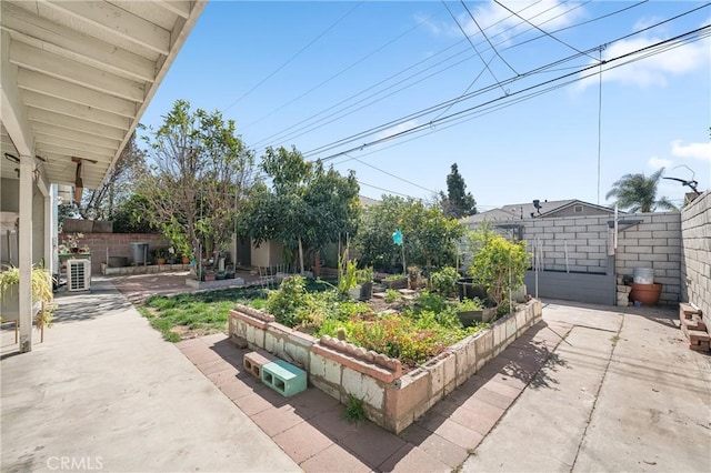 view of yard with a vegetable garden, a fenced backyard, and a patio