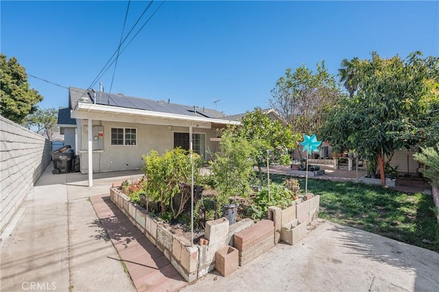 exterior space with a vegetable garden, a patio, solar panels, stucco siding, and a fenced backyard