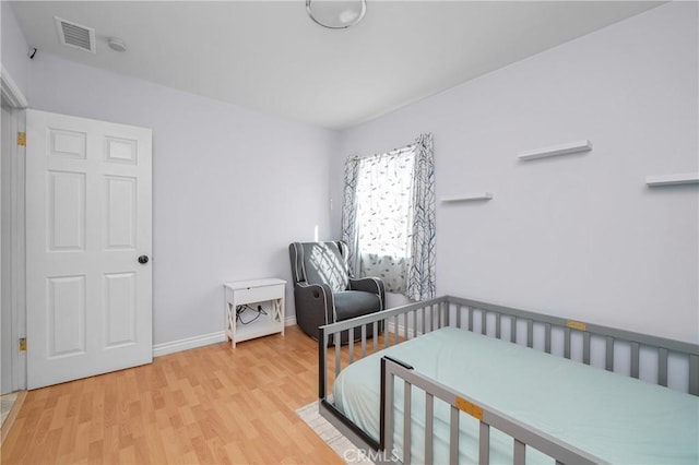 bedroom with wood finished floors, visible vents, and baseboards