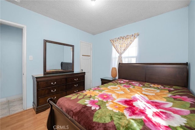 bedroom featuring a textured ceiling and light wood finished floors