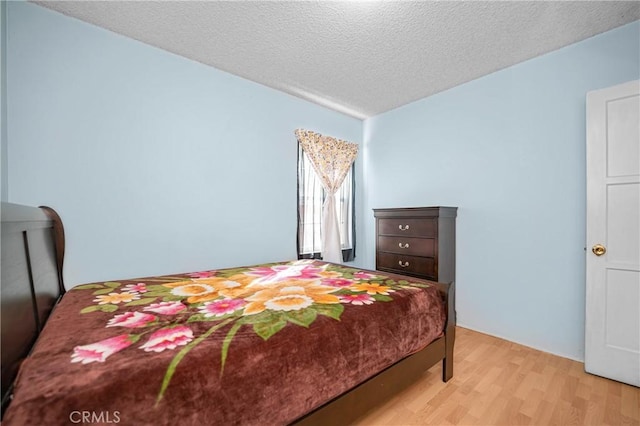 bedroom with a textured ceiling and light wood finished floors