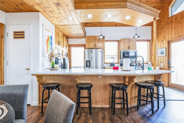 kitchen with wood ceiling, dark wood-type flooring, stainless steel appliances, light countertops, and washing machine and dryer