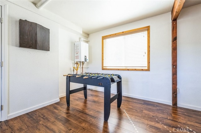 game room with dark wood-style flooring, water heater, and baseboards