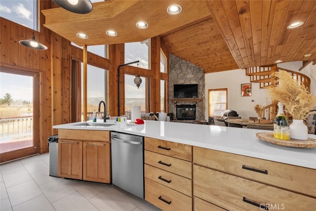 kitchen featuring stainless steel dishwasher, wood ceiling, open floor plan, a sink, and wood walls