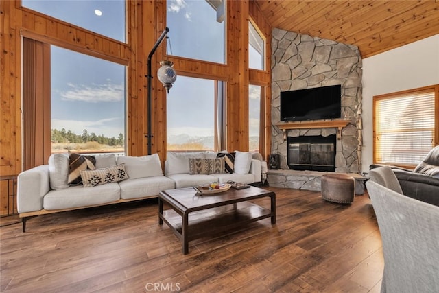 living room featuring wood ceiling, wood finished floors, wood walls, a fireplace, and high vaulted ceiling