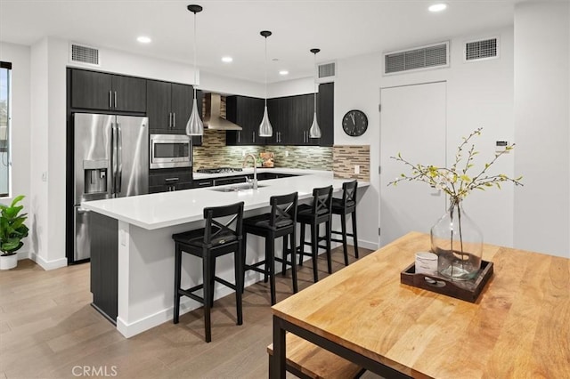1923 N Gower St, Los Angeles, CA 90068 - kitchen with appliances with stainless steel finishes, wall chimney exhaust hood, dark cabinetry, a kitchen breakfast bar, and recessed lighting