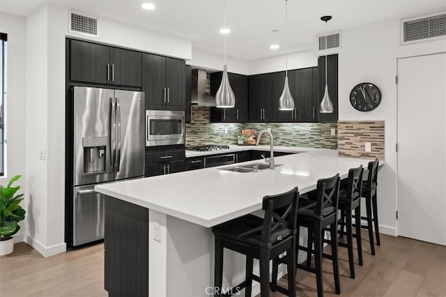 1923 N Gower St, Los Angeles, CA 90068 - kitchen with stainless steel appliances, a sink, a breakfast bar area, dark cabinets, and light wood finished floors