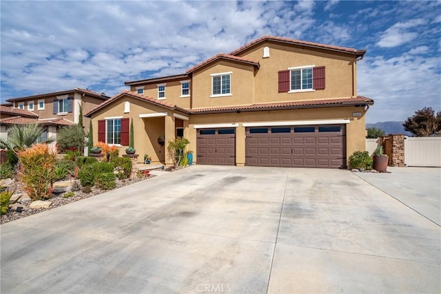 view of front of house with a garage, driveway, a tile roof, fence, and stucco siding