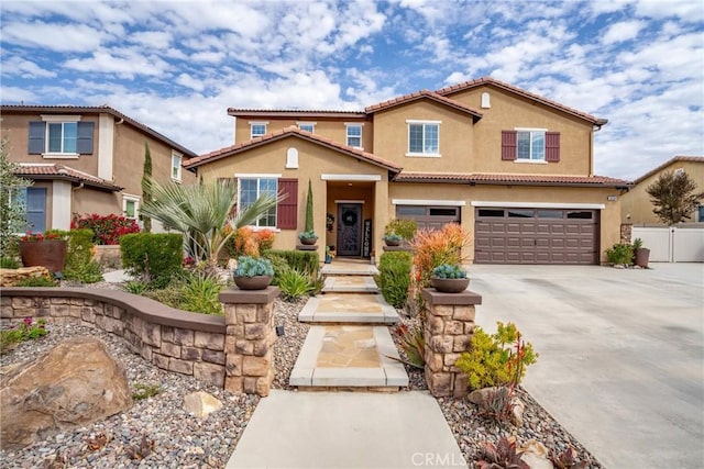 mediterranean / spanish house with concrete driveway, a tile roof, an attached garage, fence, and stucco siding