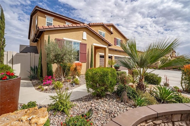 view of front of home featuring a tiled roof, fence, and stucco siding