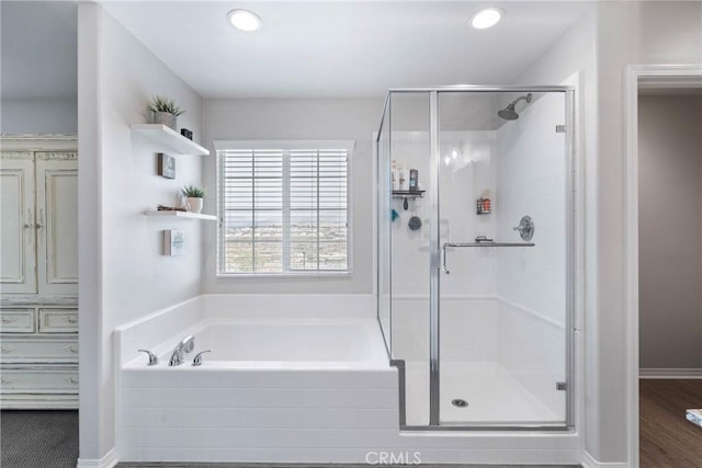 full bath with a stall shower, a bath, and recessed lighting