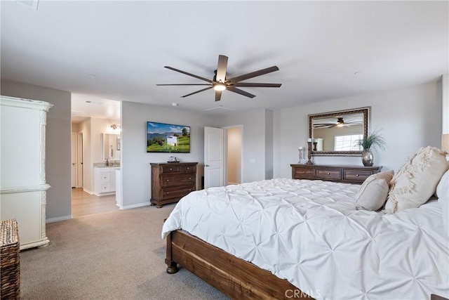 bedroom with baseboards, ensuite bathroom, a ceiling fan, and light colored carpet