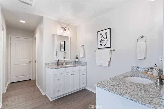 full bath with two vanities, a sink, and wood finished floors