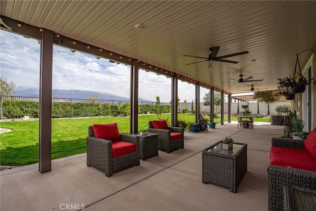 view of patio featuring fence, a mountain view, an outdoor hangout area, and a ceiling fan