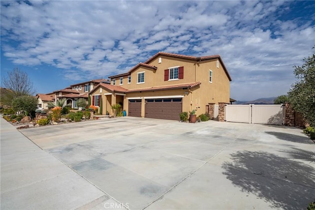 view of front of property with a tile roof, stucco siding, an attached garage, a gate, and fence