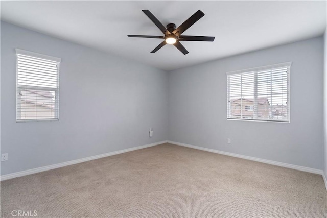 spare room with a ceiling fan, light carpet, and baseboards