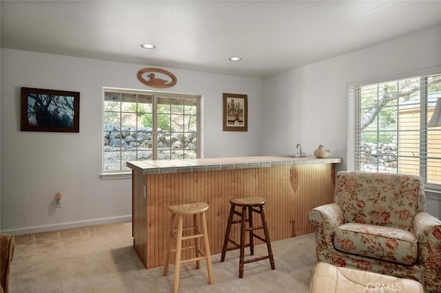 bar featuring plenty of natural light, wet bar, baseboards, and light colored carpet