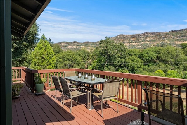 wooden deck with outdoor dining area and a mountain view