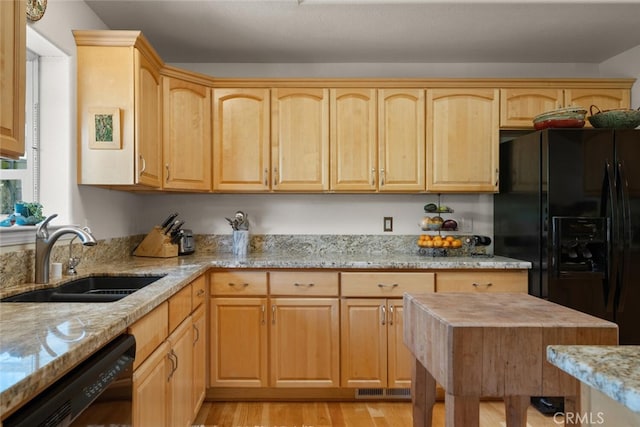 kitchen with light stone counters, light wood-style flooring, light brown cabinetry, a sink, and black appliances