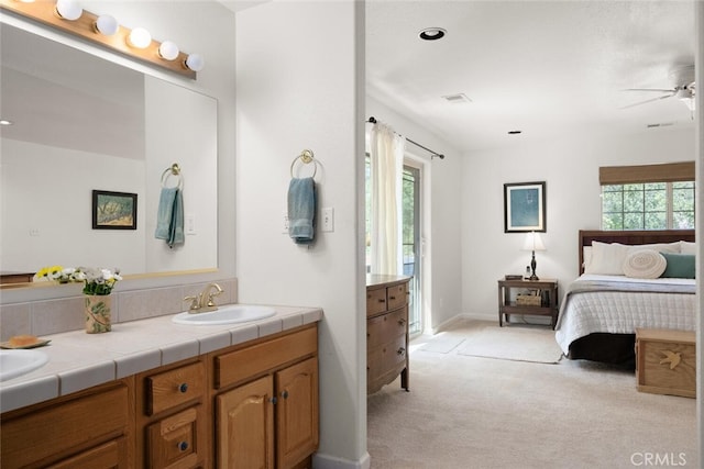 ensuite bathroom with double vanity, ensuite bath, a sink, and a healthy amount of sunlight