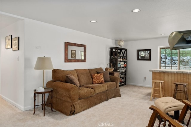 living room featuring recessed lighting, light colored carpet, a dry bar, and baseboards