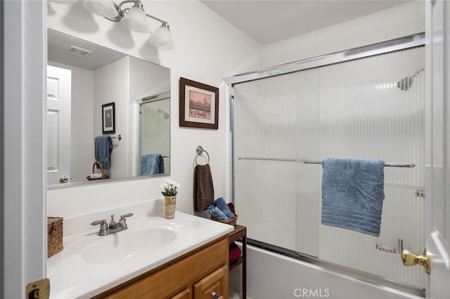 bathroom with visible vents, vanity, and combined bath / shower with glass door