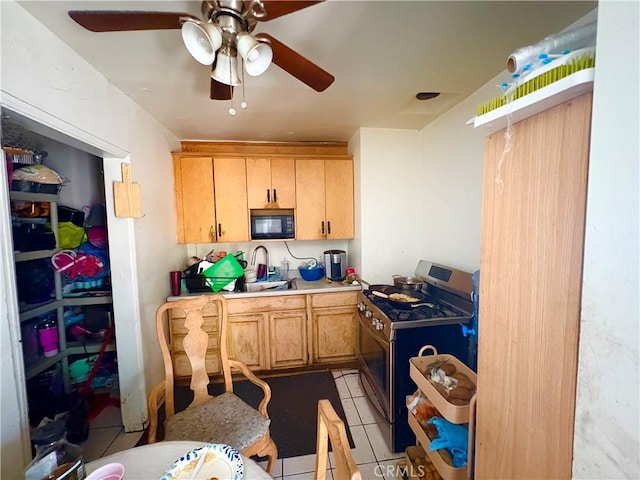 kitchen with stainless steel range with gas cooktop, light countertops, light tile patterned flooring, a sink, and black microwave