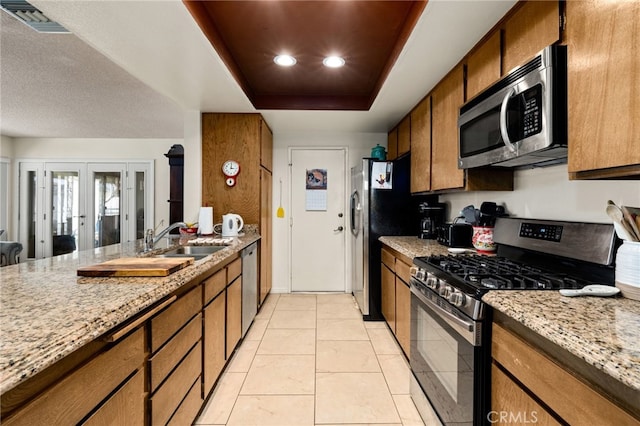 26131 Chambers Ave, Menifee, CA 92586 - kitchen featuring stainless steel appliances, a sink, brown cabinets, light stone counters, and recessed lighting