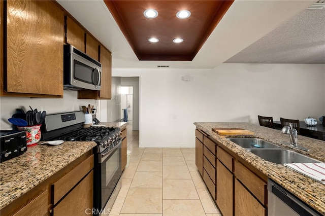 26131 Chambers Ave, Menifee, CA 92586 - kitchen featuring appliances with stainless steel finishes, a sink, a raised ceiling, recessed lighting, and brown cabinetry