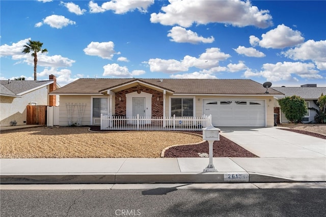 single story home with a garage, concrete driveway, brick siding, and fence