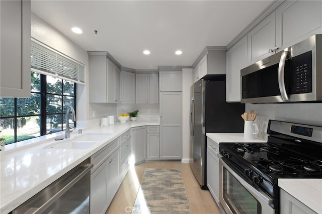 kitchen featuring stainless steel appliances, a sink, light countertops, and recessed lighting