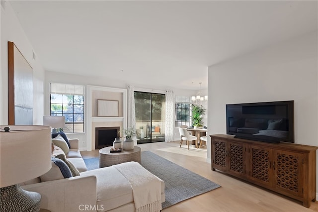 living room featuring light wood-type flooring, an inviting chandelier, and a fireplace