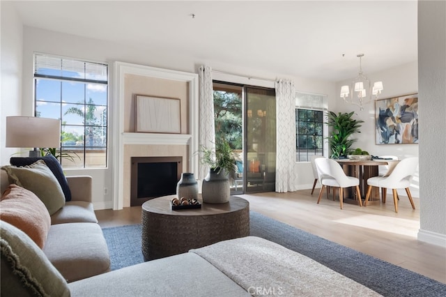 living room with baseboards, a fireplace, a chandelier, and wood finished floors