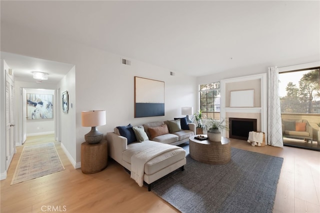 living room with baseboards, a fireplace, visible vents, and light wood-style floors